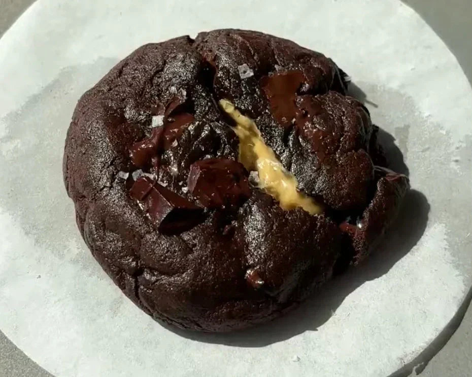 Double chocolate cookie broken open with molten pistachio spread in the center