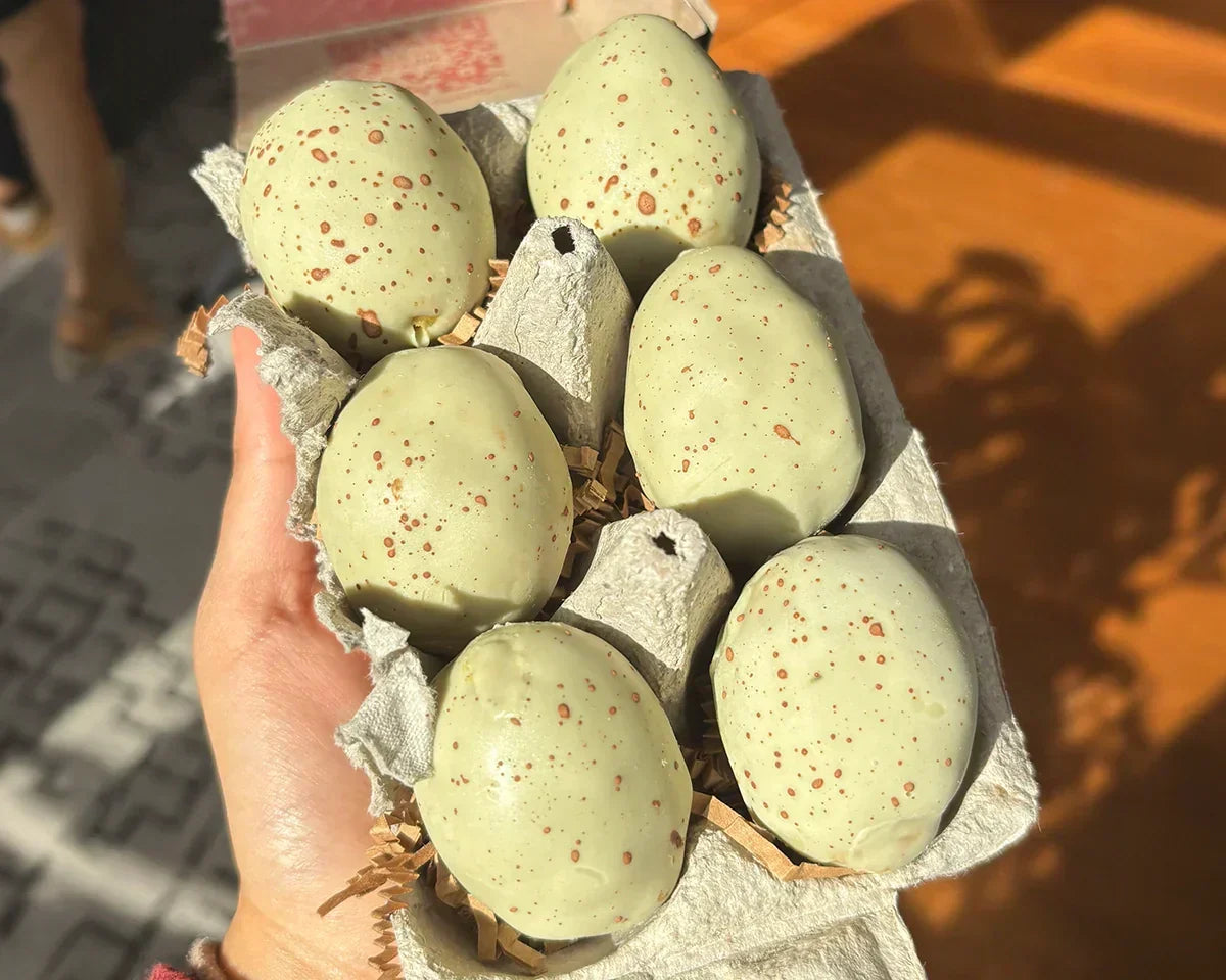 Speckled pistachio easter eggs in an egg carton with a pale green matcha shell